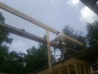 Carpenter setting a ridge beam over a new addition frame — Ice Dam Removal by Roofing Brothers in Fort Defiance