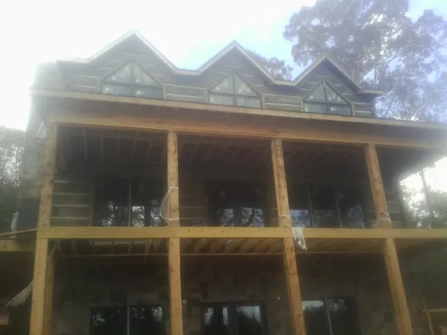 Dormers and porch framing on a large log home under construction — Roof Coating work by our crew in Fort Defiance