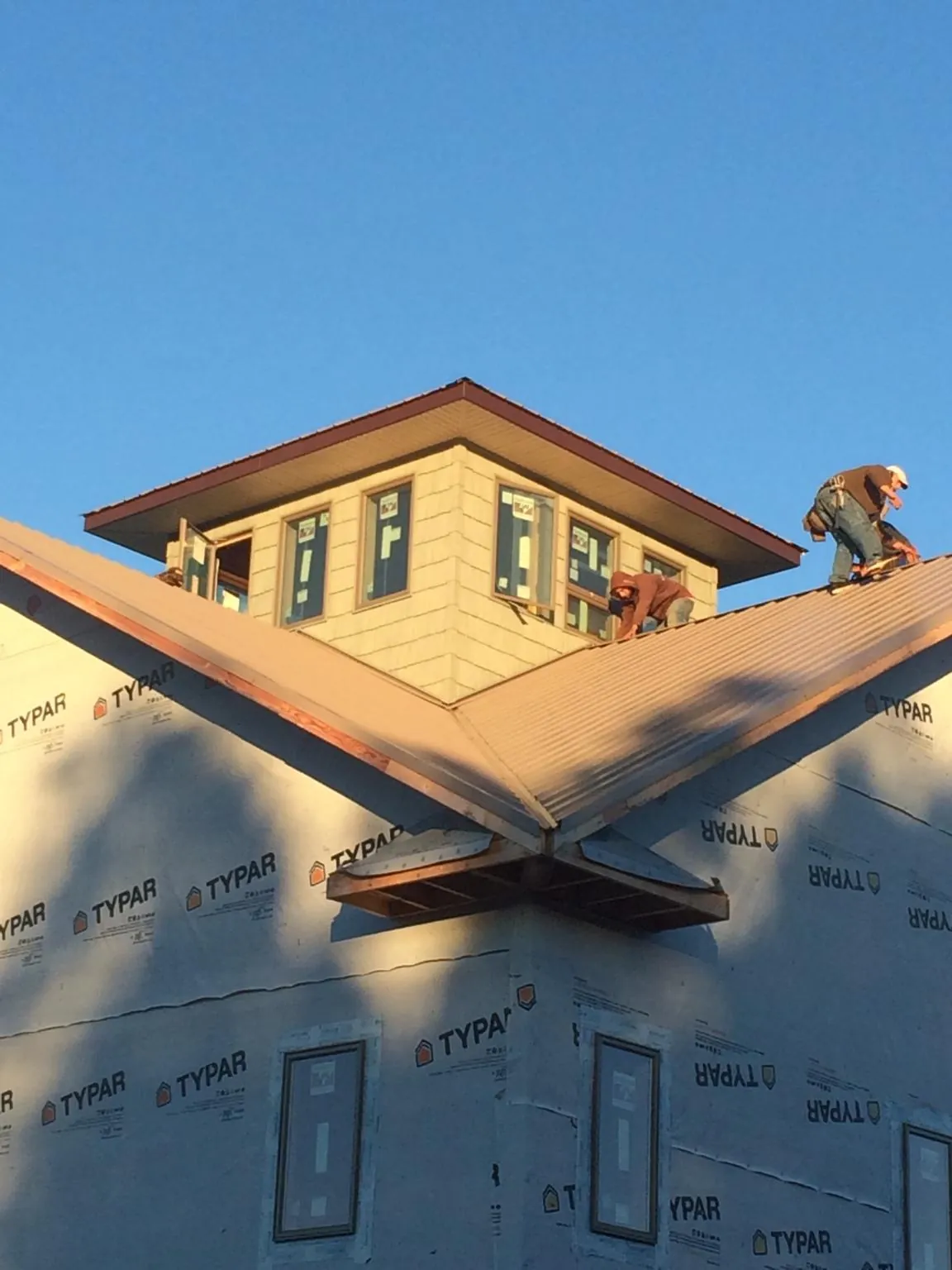 Roofers working around a rooftop cupola on a new metal roof at sunset — Roof Waterproofing in Fort Defiance by Roofing Brothers